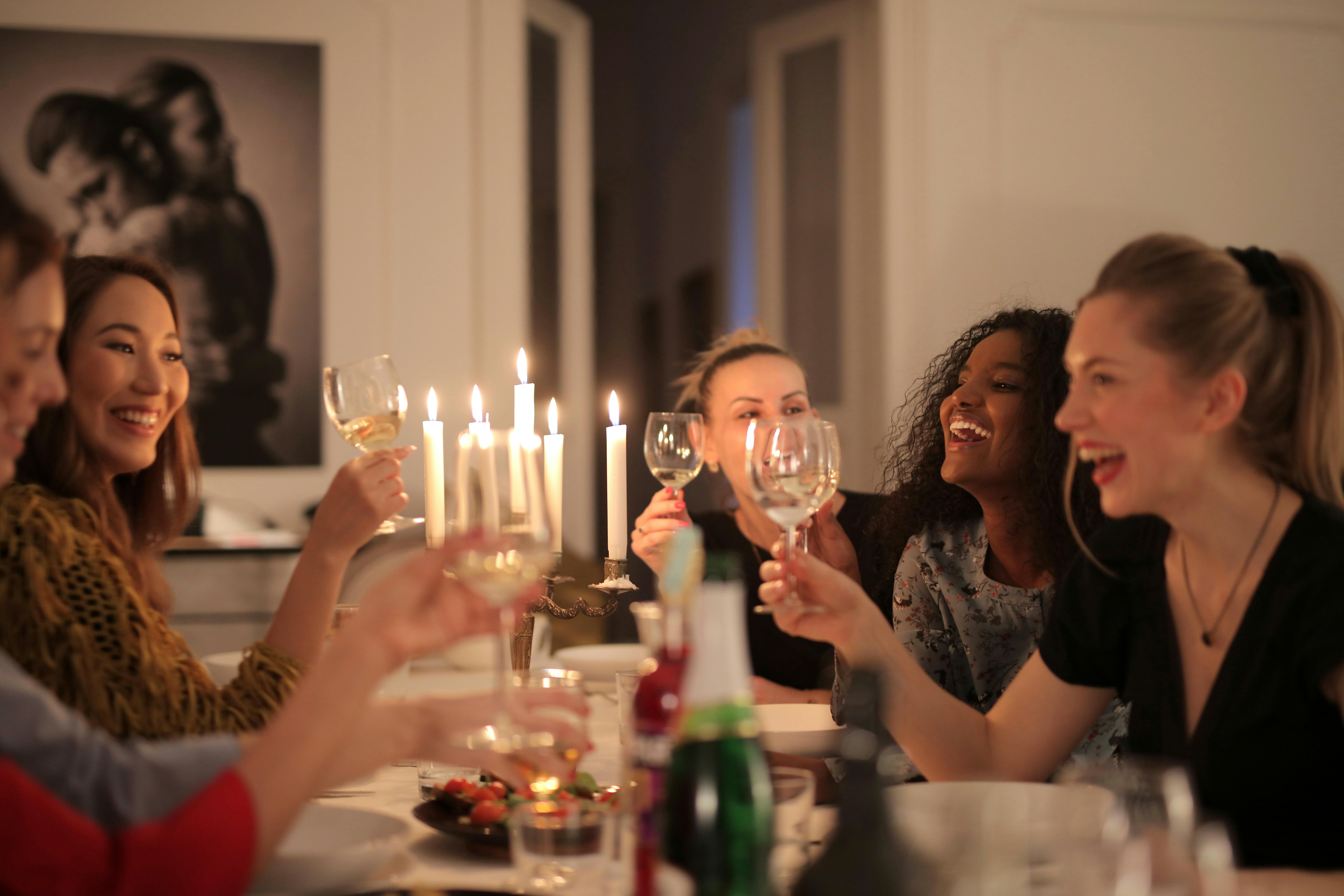 Friends laughing and toasting at a candlelit dinner table